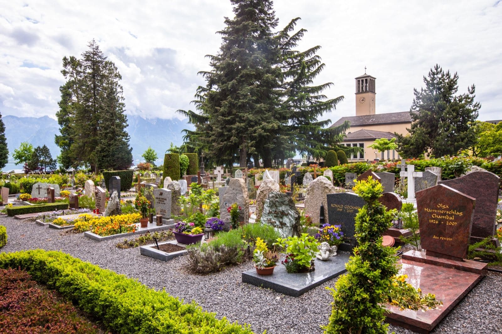 Cimetière communal paysager et fleuri au pied d une église